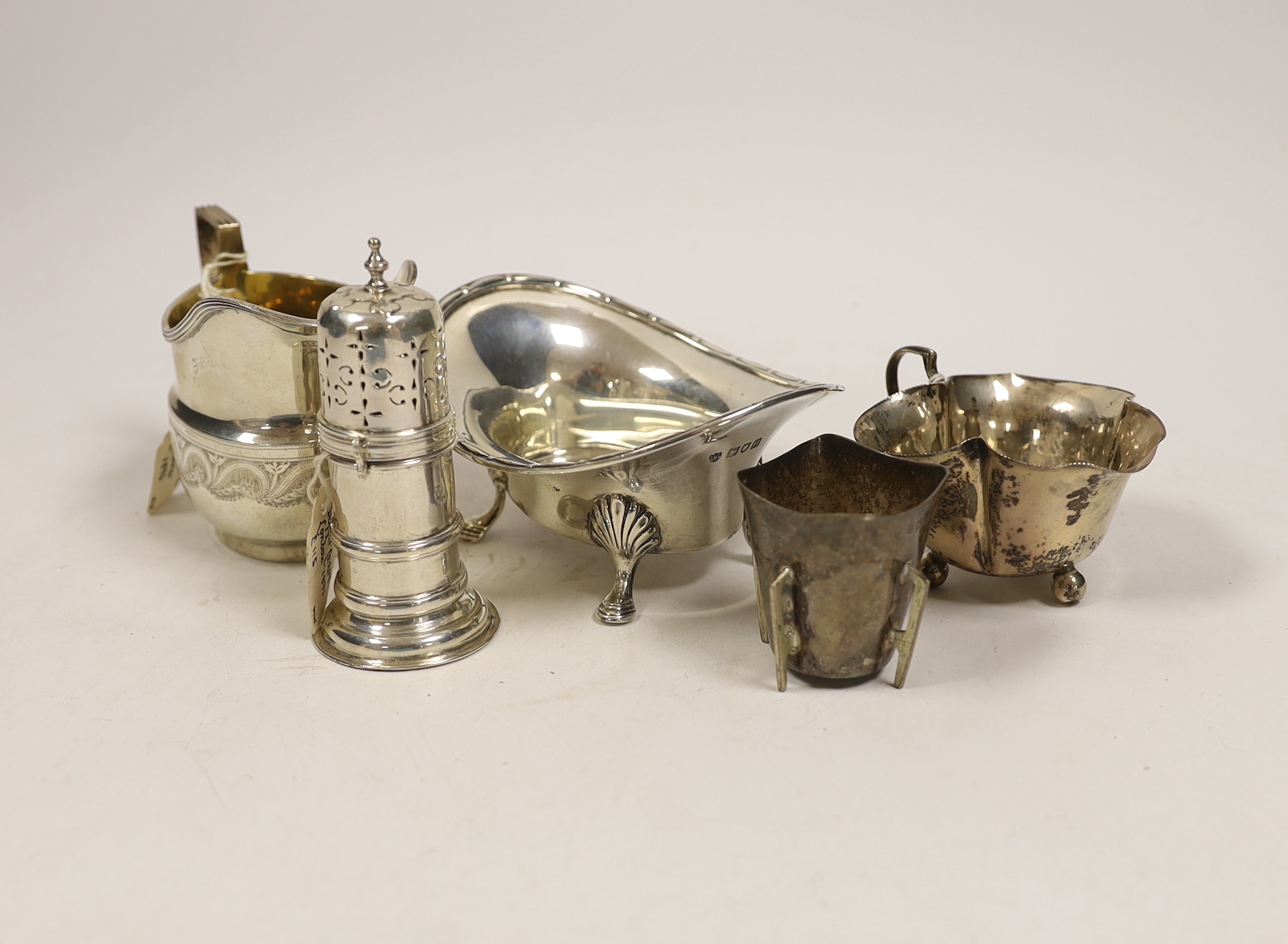 Small silverware, consisting:- a late Victorian helmet shaped cream jug, 1896; a George V oval sugar bowl, a late Victorian lighthouse sugar caster, 91mm, an Edwardian silver cream jug, 1908 and a silver tot.